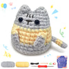 Jouet en crochet de chat gris et jaune terminé, à côté de fil et d'outils.