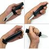 A hand holds a black retractable realistic fake knife toy, showing the blade and handle.
