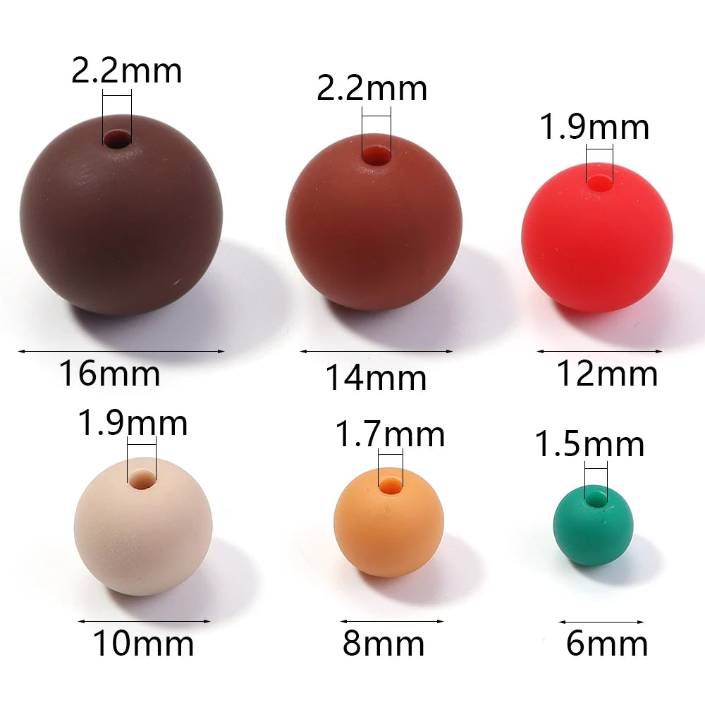 A set of matte acrylic beads in various sizes and colors, including brown, reddish-brown, red, beige, orange, and green.