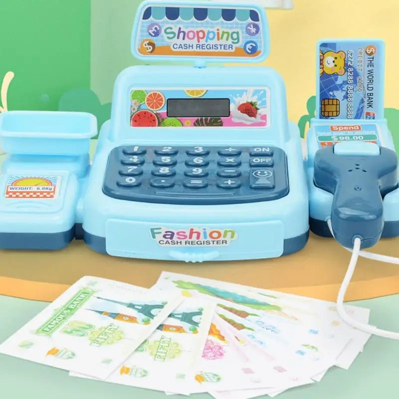 A blue interactive cash register toy with a shopping display and keypad is shown next to some paper money.