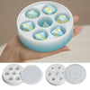 A hand holds a white silicone resin mold set with multiple hexagonal compartments for custom dice boxes.