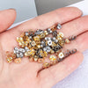 A hand holds a collection of various gold and silver stainless steel earring stud bases for DIY jewelry making.