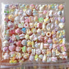 A clear plastic container filled with colorful kawaii cat paw squishy stress relief fidget toys.