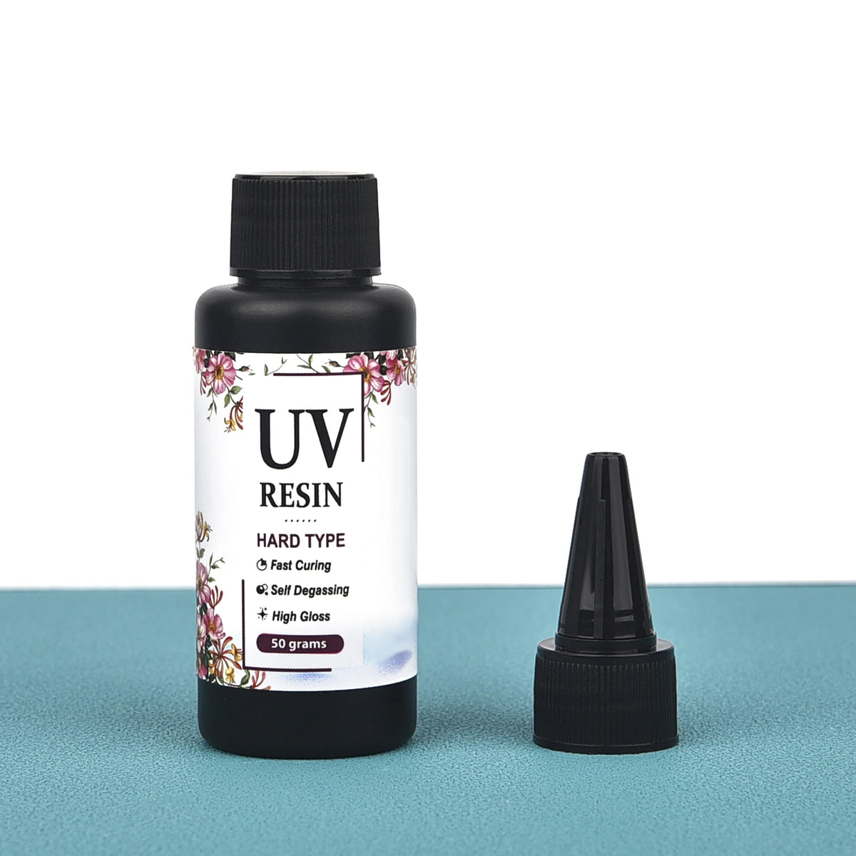 A bottle of UV resin hard type clear glue with a black dropper cap and a separate dropper shown on a teal surface.