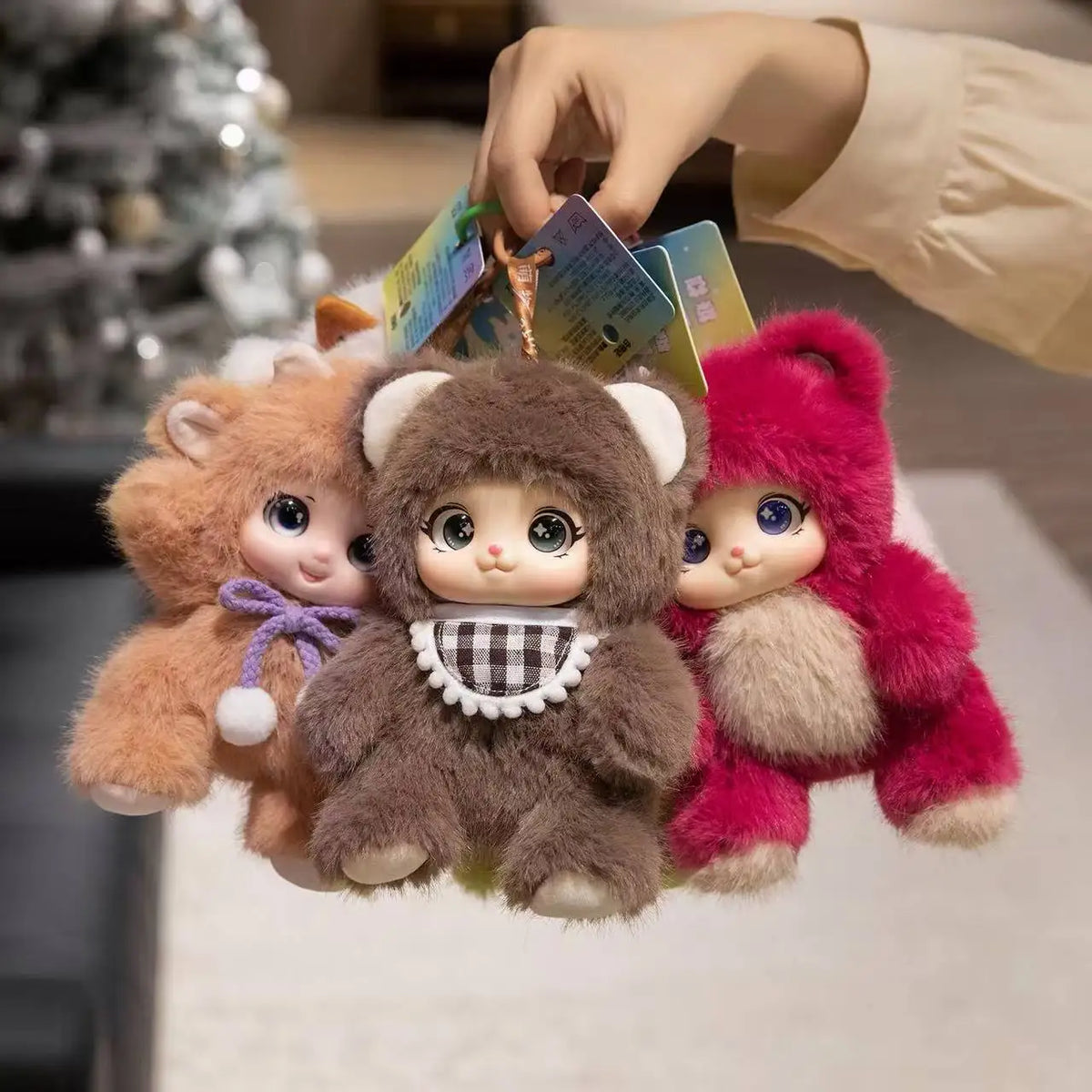 A hand is holding a collection of soft plush pendants featuring rabbit, bear, and sheep animal faces.
