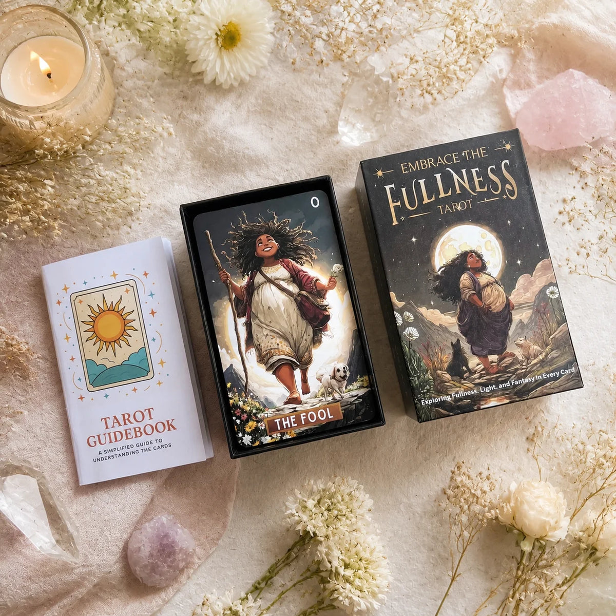A deck of Embrace the Fullness Tarot cards and a guidebook resting on light-colored fabric with dried flowers.