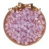 A circular display of pink glass crackle beads in a gold-toned dish.