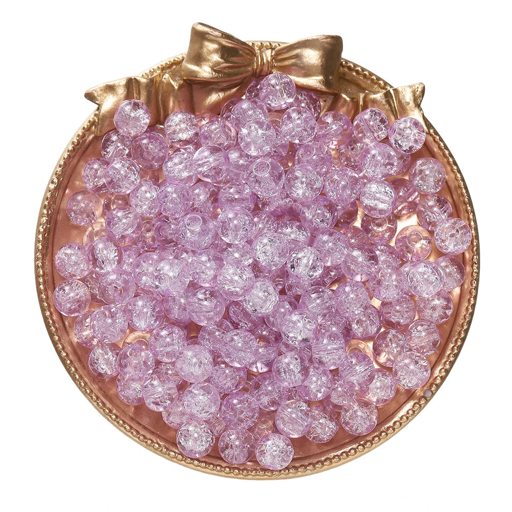 A circular display of pink glass crackle beads in a gold-toned dish.