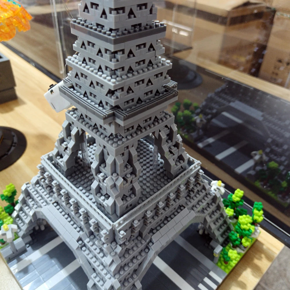 A detailed gray LEGO model of the Eiffel Tower built from micro building blocks displayed on a wooden surface.