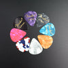 A variety pack of guitar picks in various colors and thicknesses, including purple, black, and blue shades.