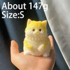 A small yellow cat shaped squishy stress relief toy is held in a person's hand.