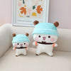 A white panda bear plush toy wearing a light blue hat and a dark belt, sitting on a light-colored surface.