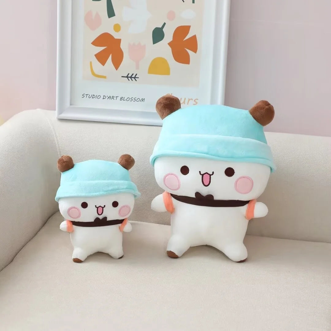 A white panda bear plush toy wearing a light blue hat and a dark belt, sitting on a light-colored surface.
