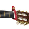 A close-up view of a red leather guitar strap button with a brass metal fastener attached to a wooden guitar neck.