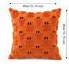 Orange textured pillow covers featuring a pattern of black ghost faces for Halloween decoration