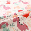 Close-up of a fabric featuring a grid print pattern of pink, teal, and orange dinosaurs for sewing and crafts.