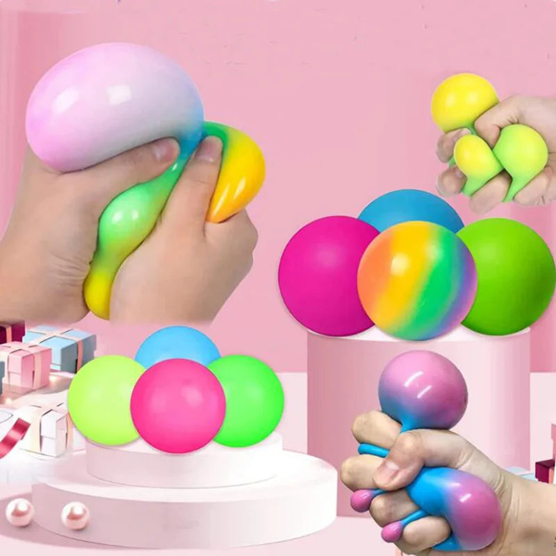 Hands are squeezing colorful slow rising squishy stress balls in various shades of pink, green, and yellow.