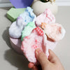 A hand is squeezing a pink squishy stress relief ball fidget toy with various pastel colored squishies in the background.