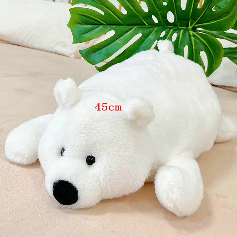 A white plush polar bear stuffed animal lying on a light surface with a green tropical leaf in the background.