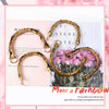 Golden bamboo-style bag handles displayed against a pink floral background.