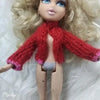 A doll with blonde hair wearing a red knitted sweater and a matching scarf.