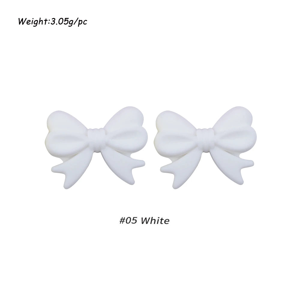 A pair of white silicone bow tie beads for jewelry making and craft projects.