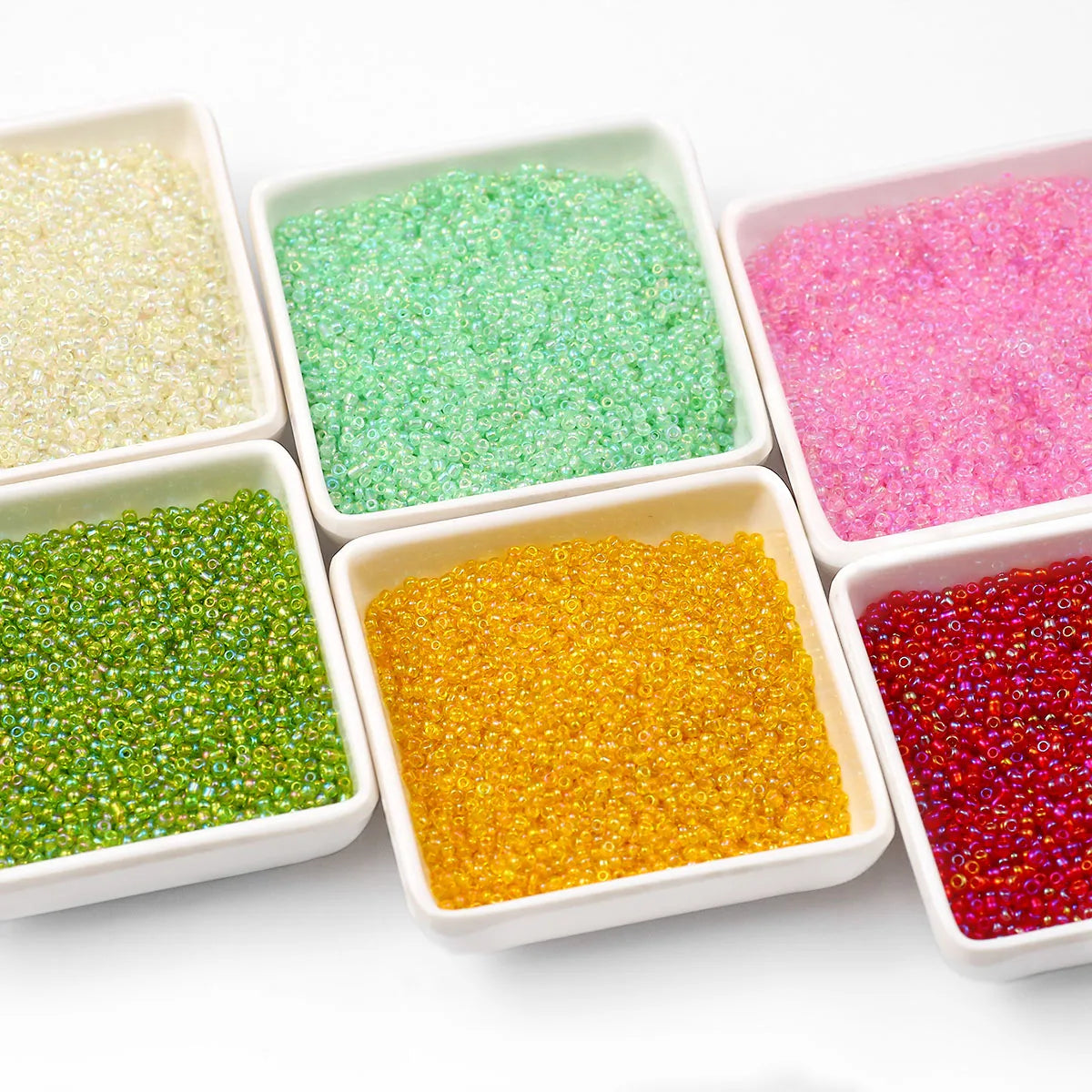 A collection of brightly colored, glossy glass seed beads in various shades including green, pink, and orange, displayed in s