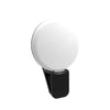 A portable LED selfie ring light with a white circular light and a black clip.