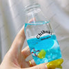 A hand holds a clear bottle filled with blue liquid labeled Chiboki drink cup toy