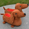 A brown dachshund plush toy with floppy ears and red interior lining is resting on a gray surface.