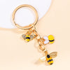 Gold enamel flower keychain featuring a bee and daisy design