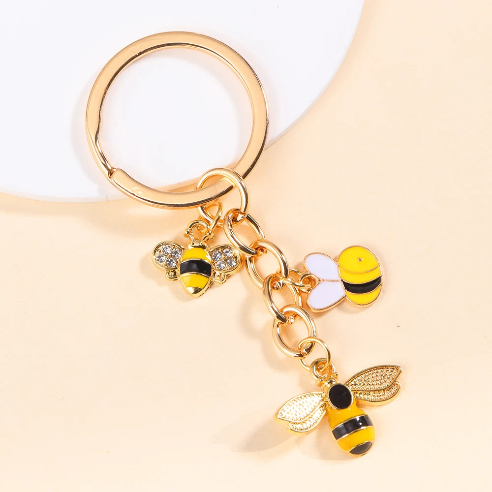 Gold enamel flower keychain featuring a bee and daisy design