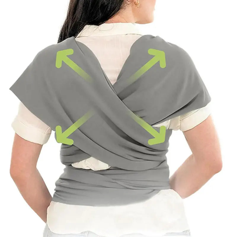 A person wearing a gray ergonomic multi-functional baby sling carrier, demonstrating its folding design.