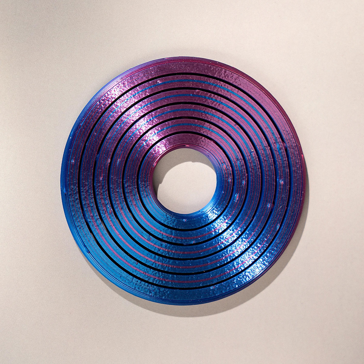 A circular ring made of iridescent blue and purple plastic, featuring concentric ridges.