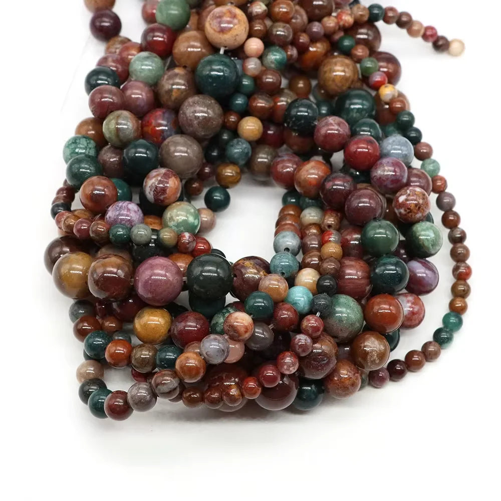 A collection of natural stone round beads in various shades including rose quartz, amethyst, and red silk jade.