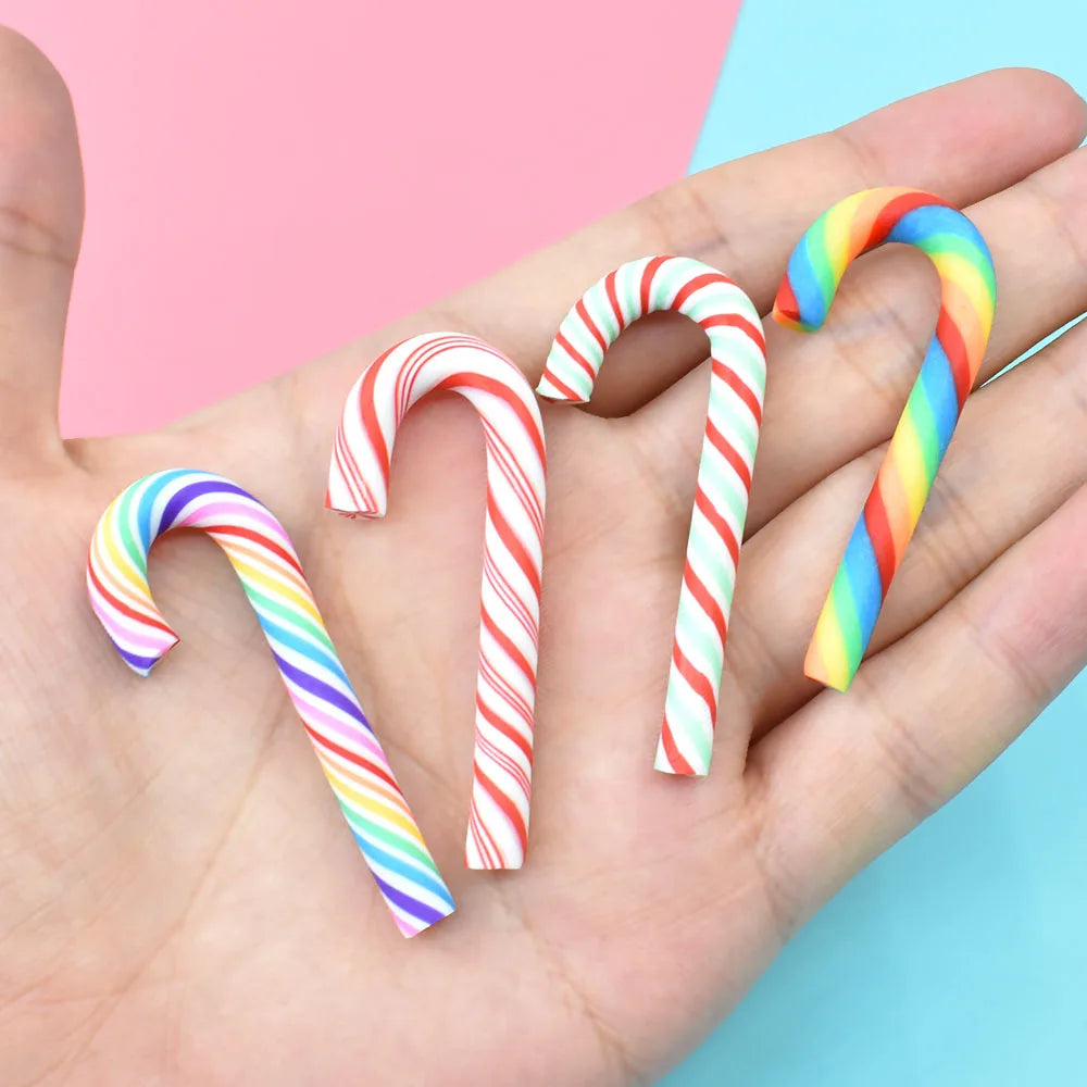 A hand holds ten colorful striped polymer clay marshmallow charms in various rainbow colors and shapes.