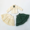 A vintage lace maid dress set for dolls featuring a cream-colored blouse and a matching green ruffled skirt.