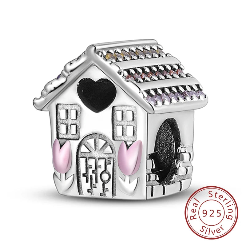 A sterling silver charm shaped like a house with decorative details and a black heart.