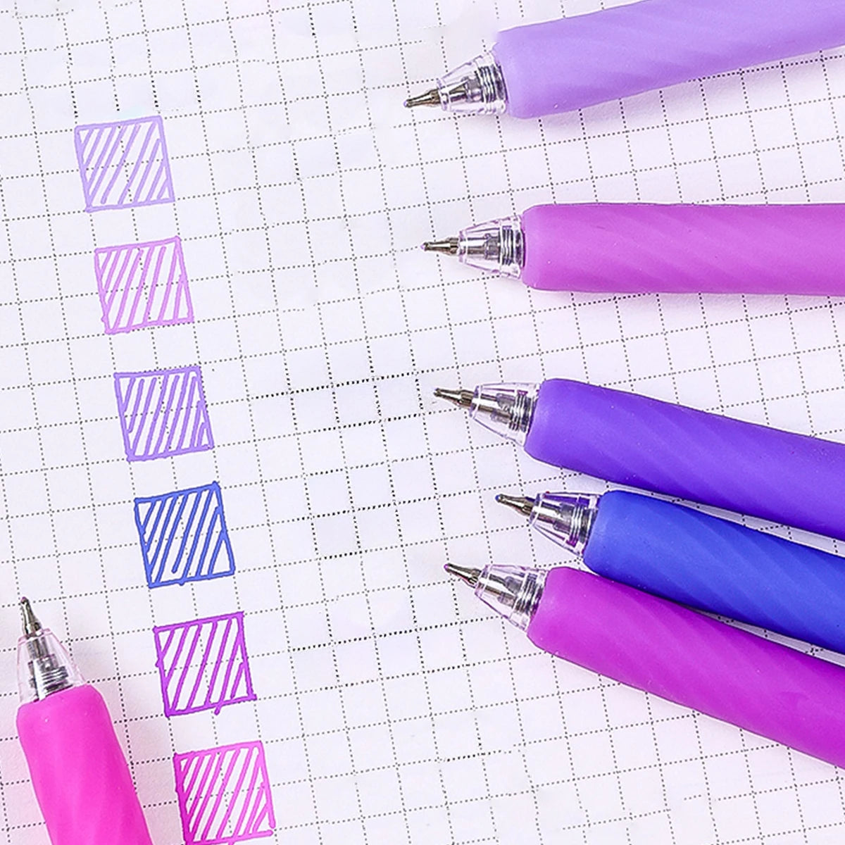 A collection of six retractable gel pens in various shades of purple and blue are arranged vertically on a white grid.