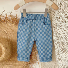 Light blue and white plaid corduroy pants for toddlers hanging on a wooden hanger
