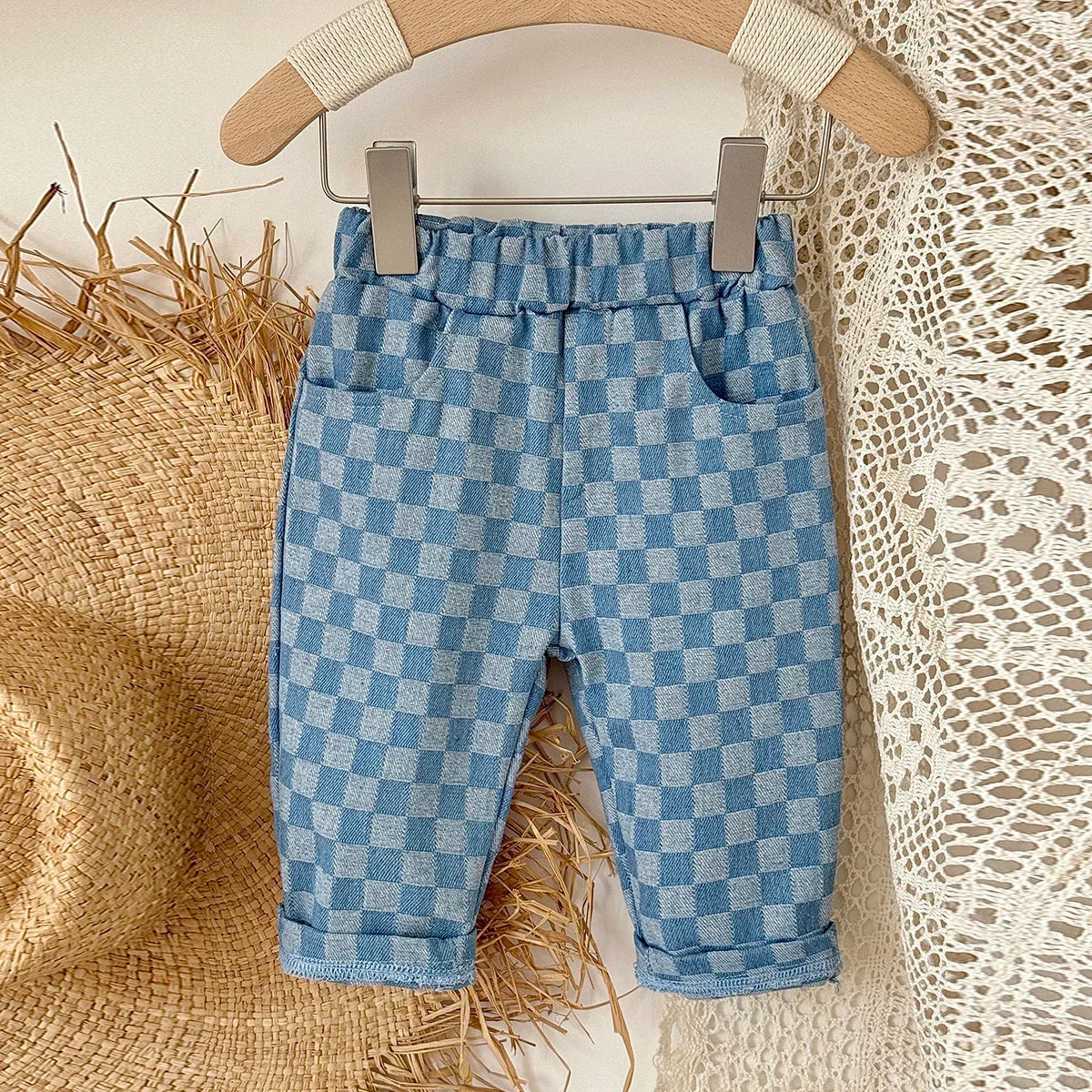 Light blue and white plaid corduroy pants for toddlers hanging on a wooden hanger
