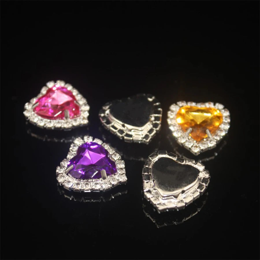 A collection of heart-shaped flatback sew-on rhinestones in various colors including pink, yellow, and purple, displayed on a