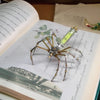 A detailed steampunk metal spider model is displayed on an open book page.