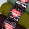 A close-up of three skeins of super soft green and brown acrylic yarn labeled with a heart design.