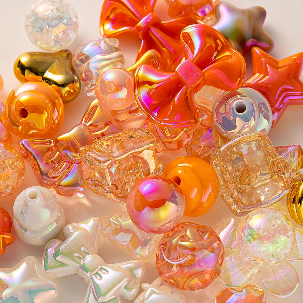 A collection of colorful acrylic bow and flower beads in shades of orange, pink, and clear are displayed for DIY jewelry maki