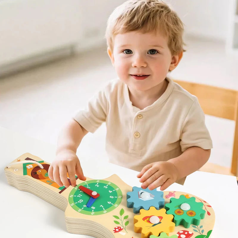 A smiling toddler holds a wooden busy board featuring musical and sensory activities.