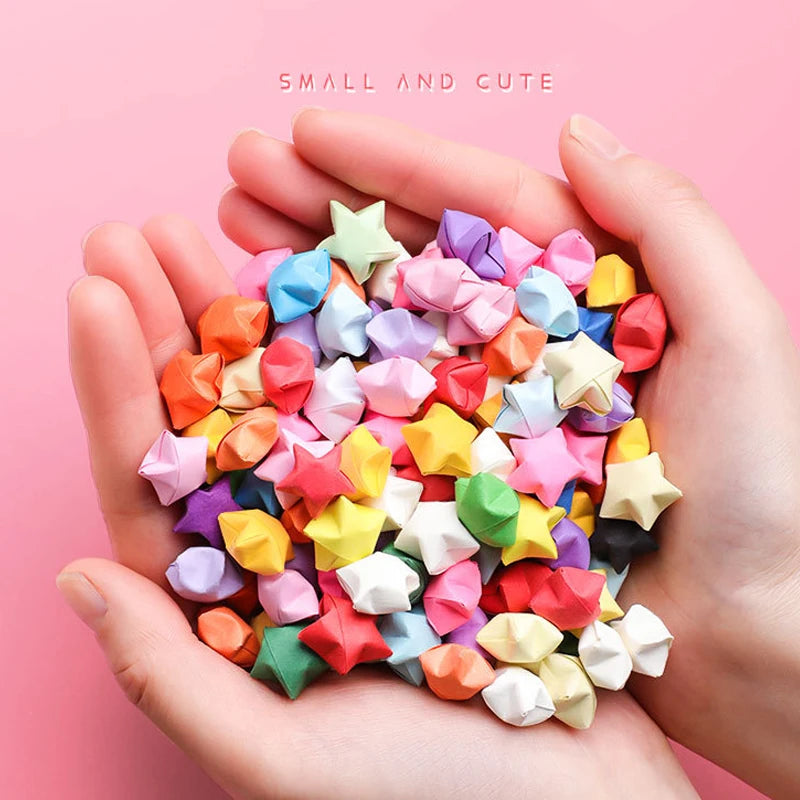 Hands holding a pile of colorful origami star strips for DIY crafting