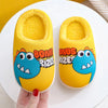 A pair of yellow plush slippers shaped like cartoon dinosaurs with bright blue accents resting on a white plate.