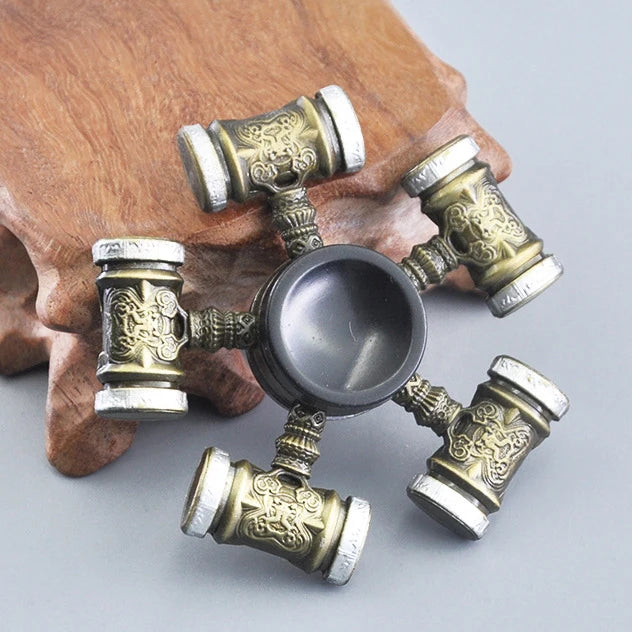 A metal fidget spinner with a rainbow finish resting on a wooden surface.