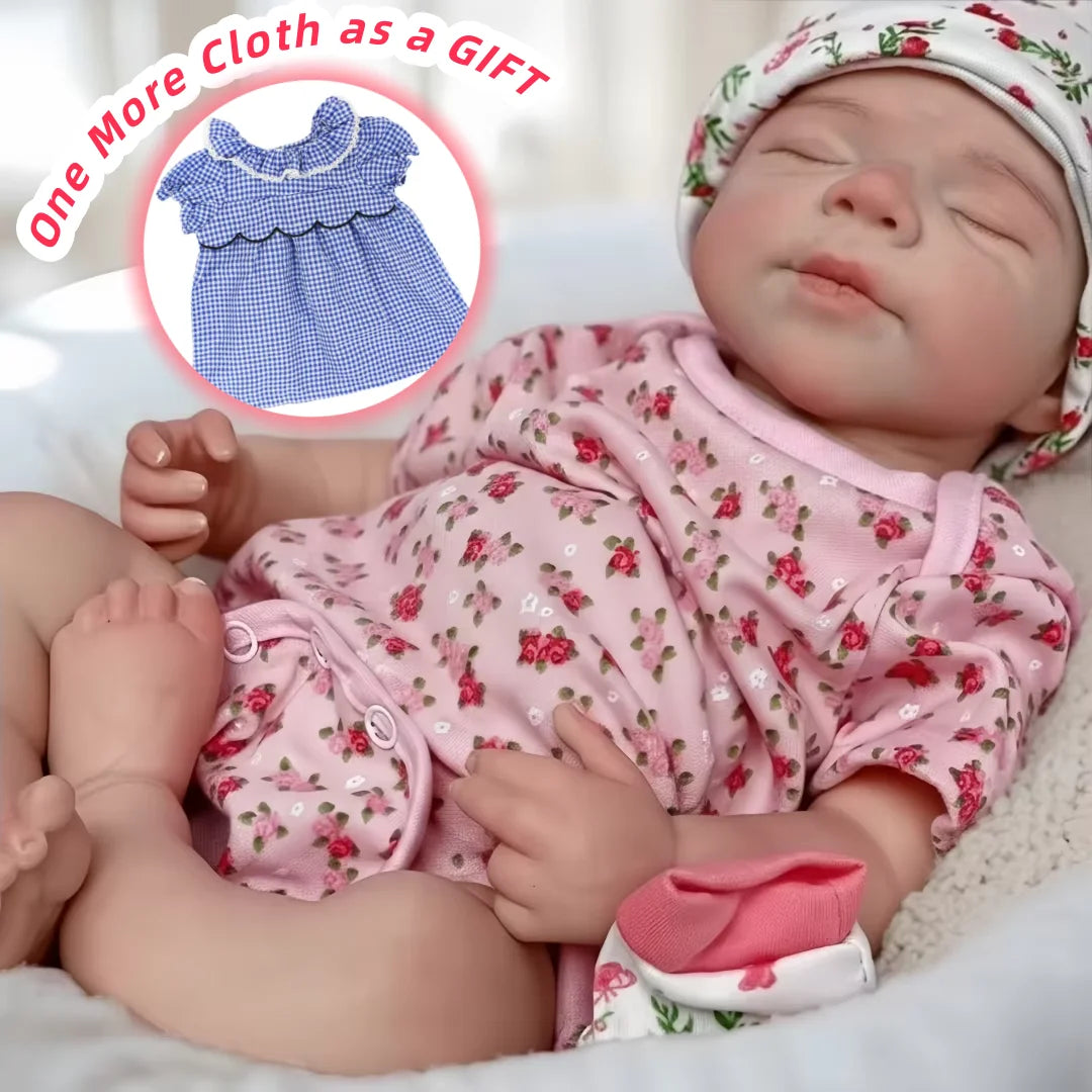 A lifelike 18-inch silicone reborn baby doll named Pascale wearing a pink floral outfit is shown sleeping.